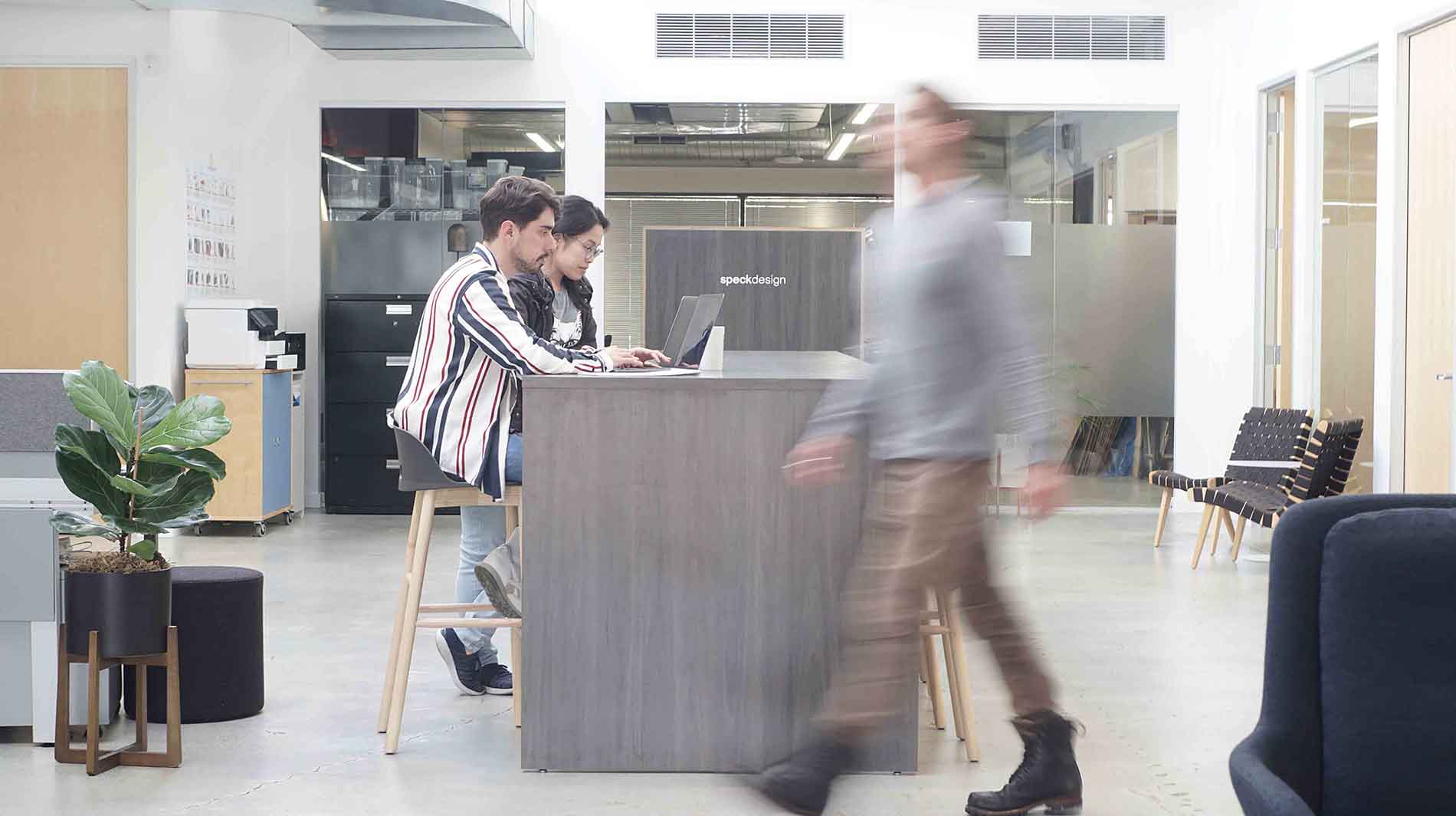 Blurred office photo of employees walking at Speck, a product design company